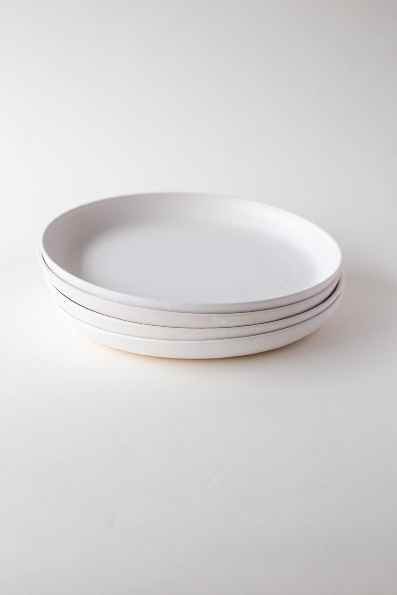 A handthrown and unique ceramic dinner plate in an off white glaze. The Kinship Collection